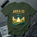 Green t-shirt with vintage flat-graphic illustration of a saucer beaming light over a Nevada desert highway with AREA 51 TOURIST text in gold and white
