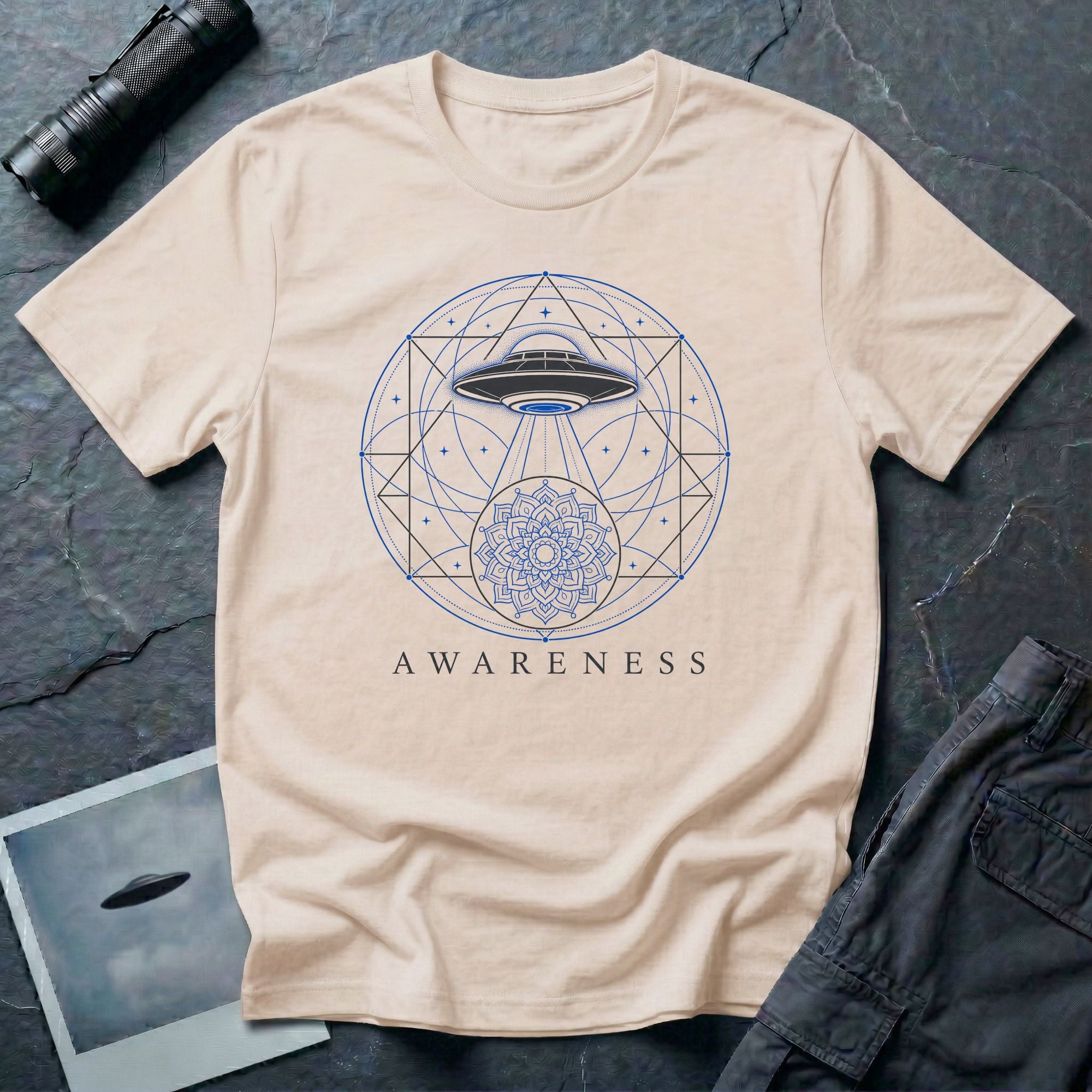 Sacred geometry UFO t-shirt, craft with light beam descending through geometric circles and triangles into a mandala, the word Awareness below, natural