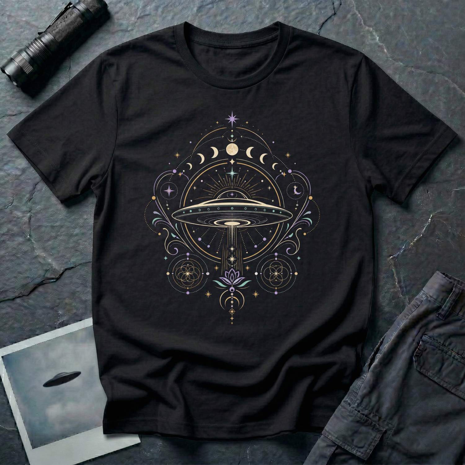 Black t-shirt with a celestial mandala UFO design featuring lunar phase sequence lotus flower seed of life geometry and central saucer in gold lavender and teal linework
