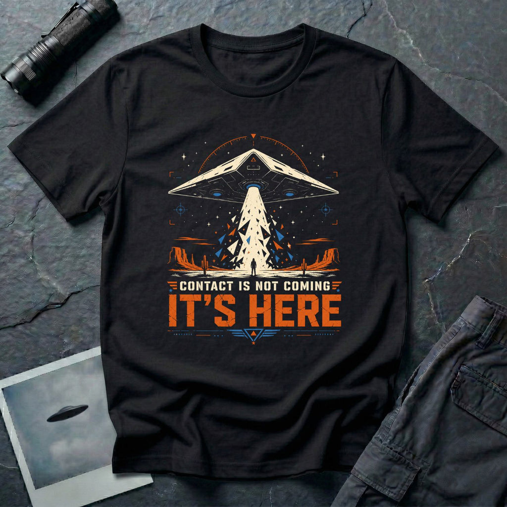 Black t-shirt with cinematic triangular TR-3B UAP craft firing geometric beam shards onto lone human figure in desert landscape with CONTACT IS NOT COMING IT'S HERE text in white and orange