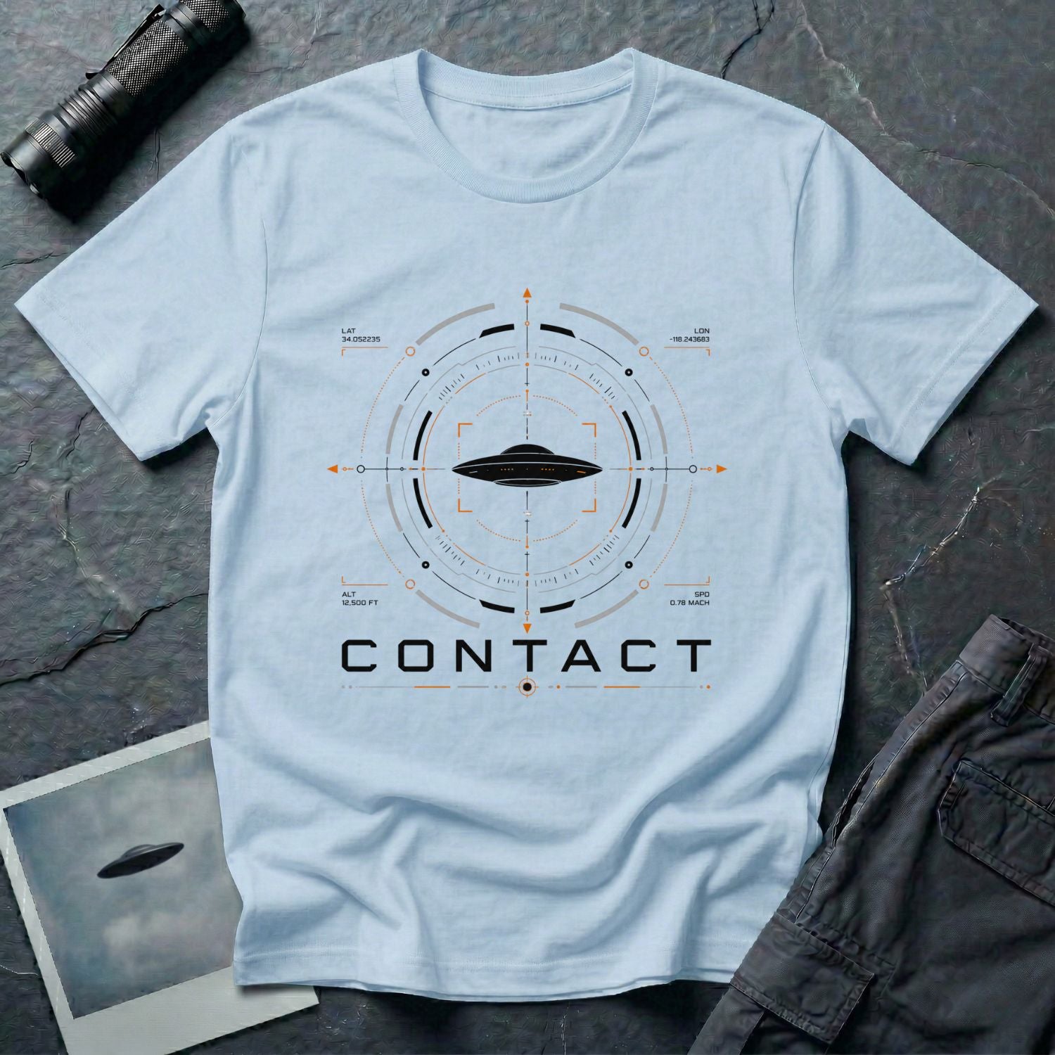 Light blue UAP t-shirt with a flying saucer inside a military radar targeting interface showing Los Angeles coordinates, altitude, and speed data with the word CONTACT