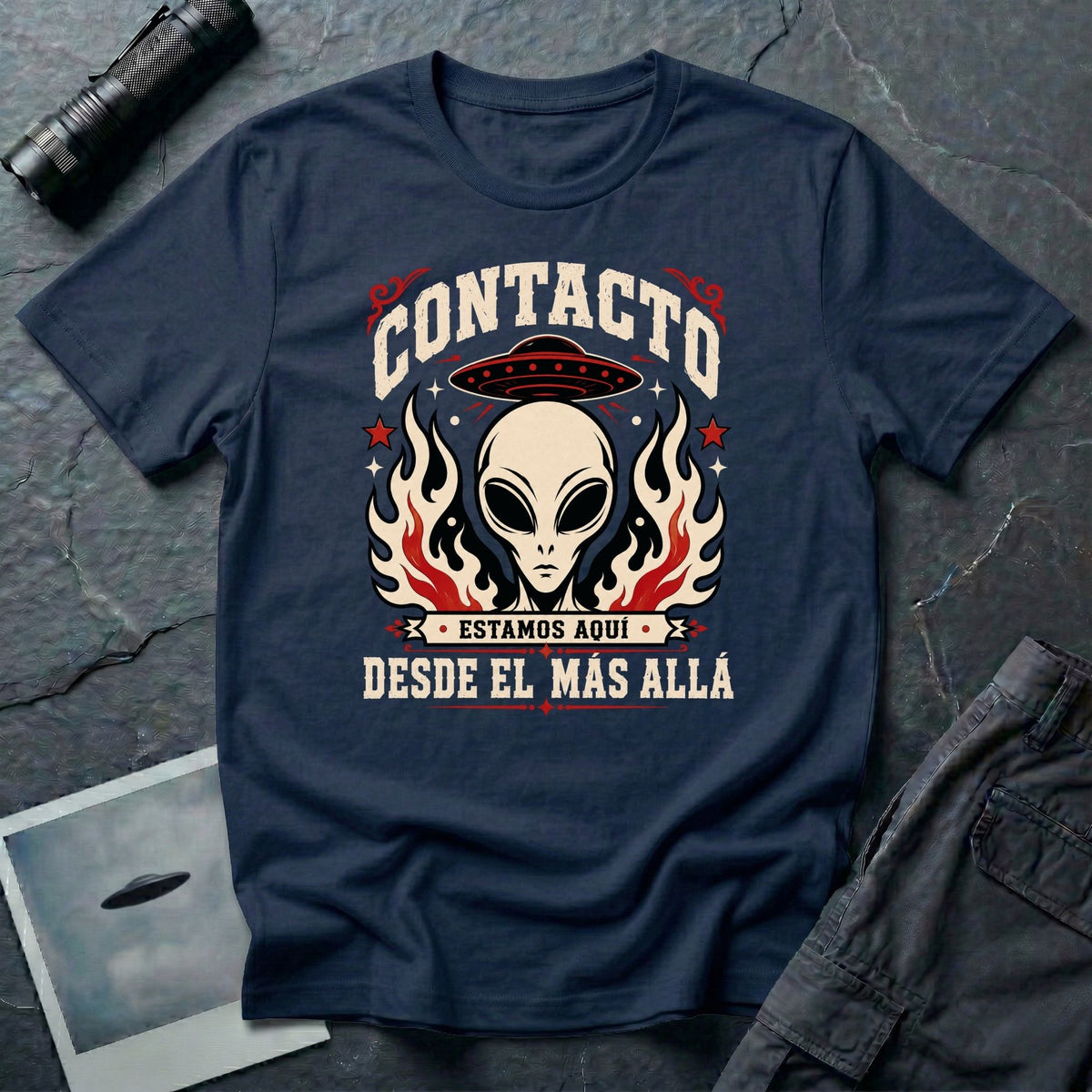 Navy blue t-shirt with vintage rock poster style alien head, UFO, and Spanish text reading Contacto Estamos Aquí Desde El Más Allá