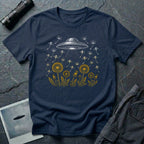 Dandelion UFO Fleet t-shirt with gold botanical dandelions releasing seed saucers toward a white mothership, navy blue tee