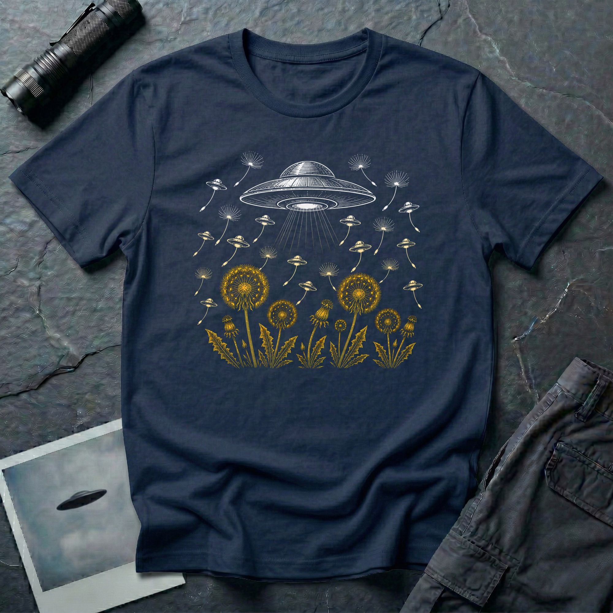 Dandelion UFO Fleet t-shirt with gold botanical dandelions releasing seed saucers toward a white mothership, navy blue tee