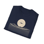 Desert Crossing UFO T-shirt with a black flying saucer crossing a white moon above minimalist line-art desert dunes, navy blue tee