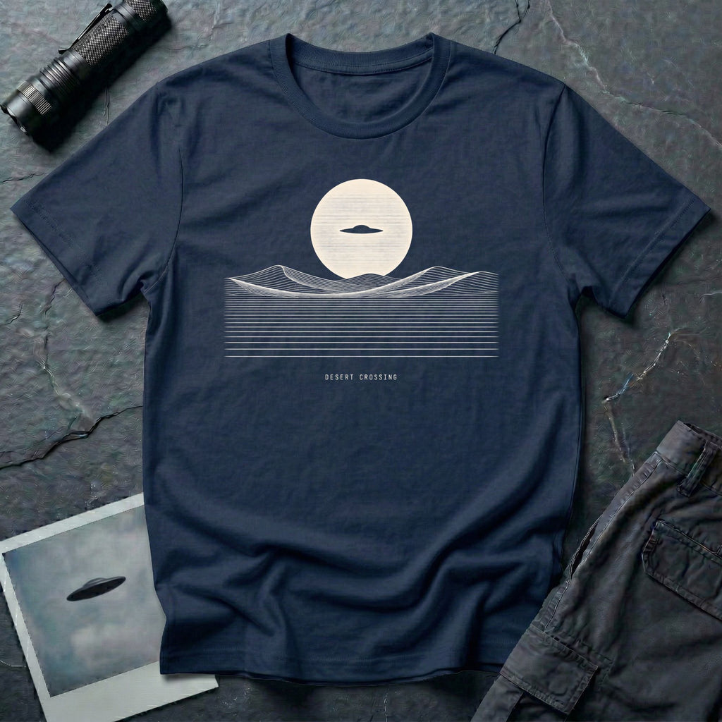 Desert Crossing UFO T-shirt with a black flying saucer crossing a white moon above minimalist line-art desert dunes, navy blue tee