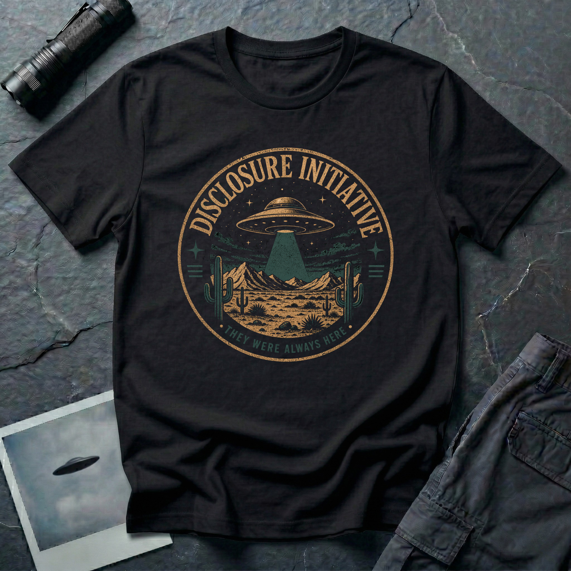 Black t-shirt with a circular vintage badge showing a saucer UFO over a desert scene with cacti and mountains, labeled Disclosure Initiative.