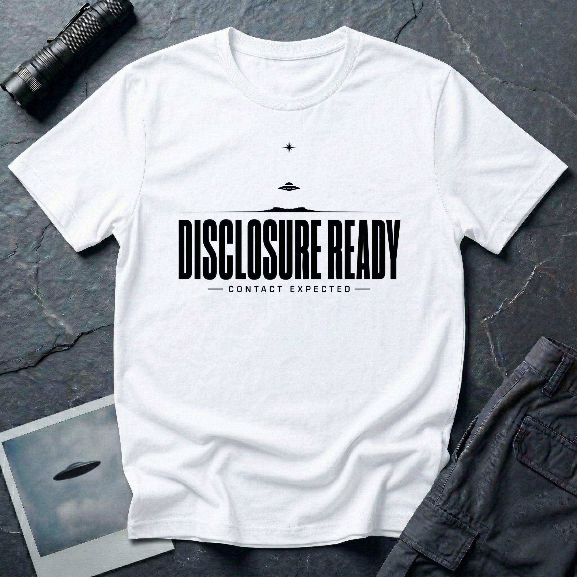 White UFO disclosure t-shirt with bold block letters reading DISCLOSURE READY and subtitle CONTACT EXPECTED with a small flying saucer above the horizon in black