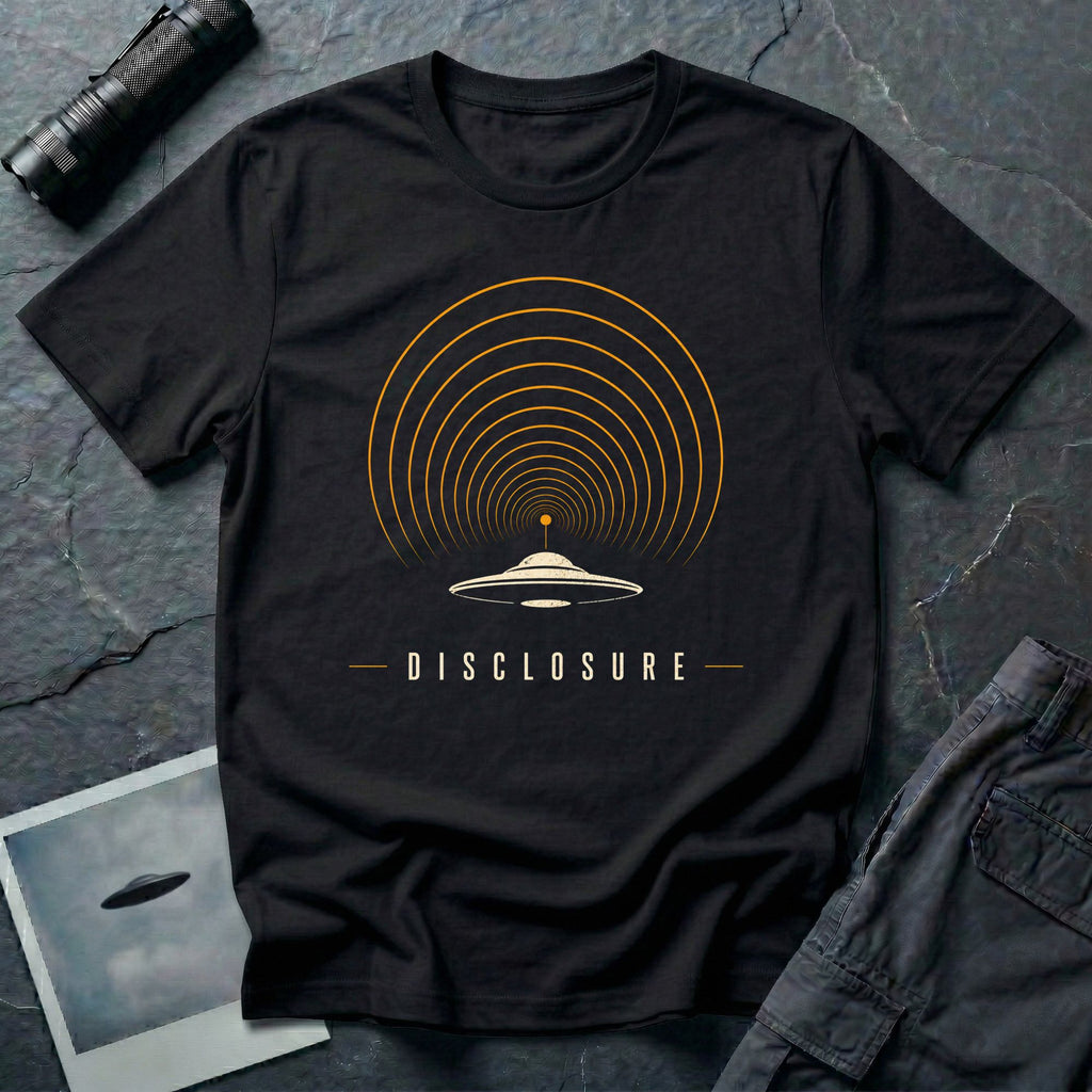 Black UFO disclosure t-shirt with a flying saucer broadcasting concentric signal arcs upward in orange and cream with the word DISCLOSURE beneath