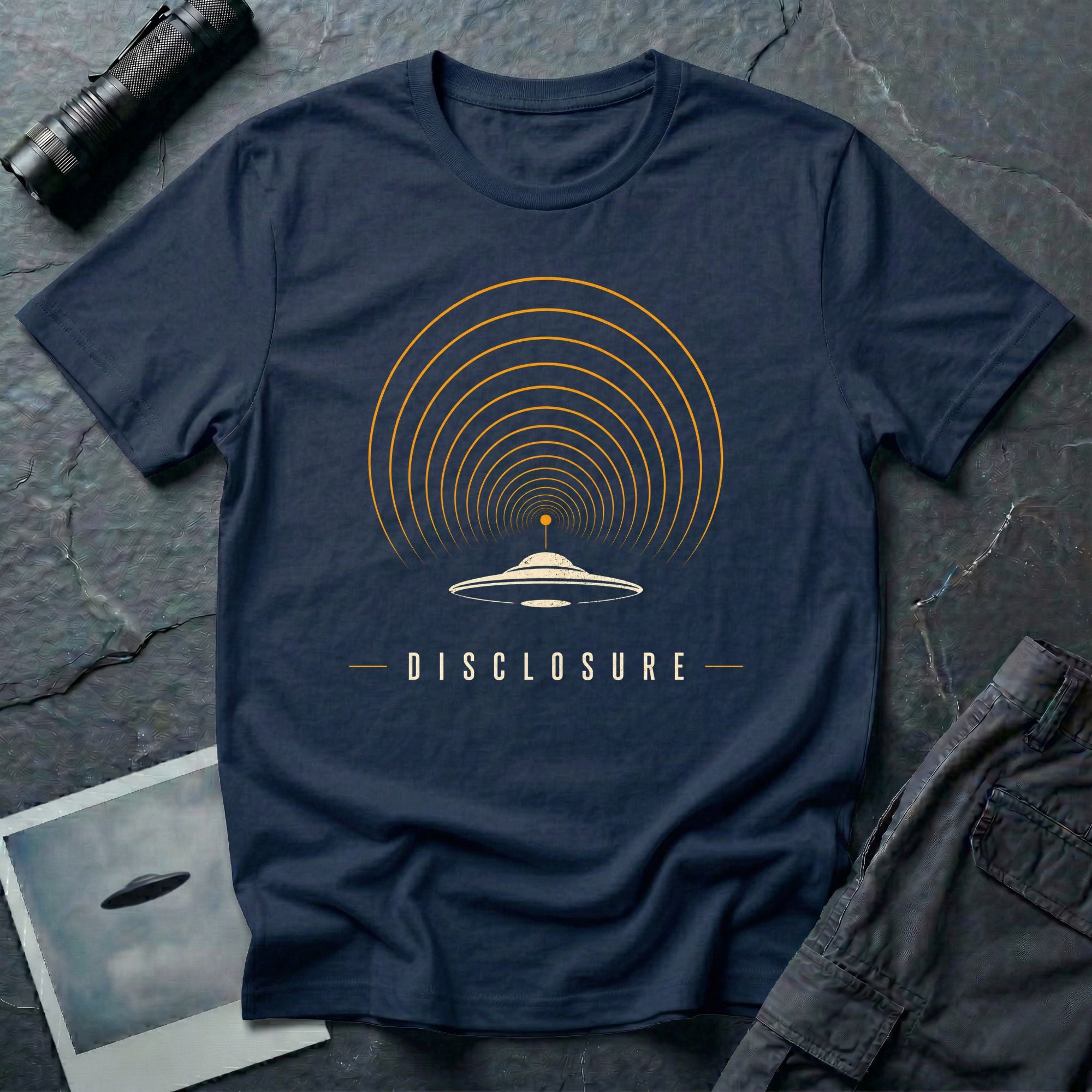 Navy blue UFO disclosure t-shirt with a flying saucer broadcasting concentric signal arcs upward in orange and cream with the word DISCLOSURE beneath