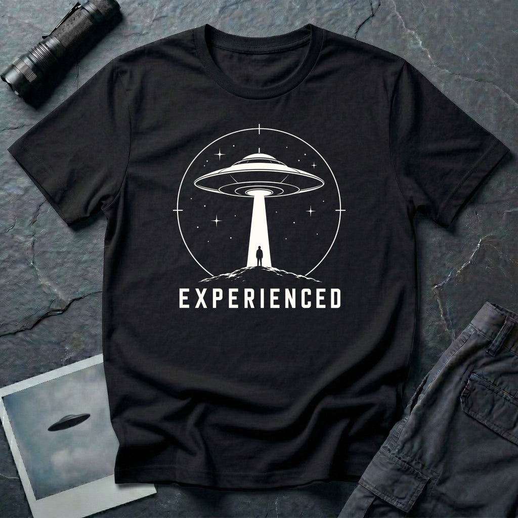 Experienced UFO T-shirt with a lone figure standing beneath the beam of a flying saucer inside a circular night-sky design. Black tee