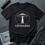 Experienced UFO T-shirt with a lone figure standing beneath the beam of a flying saucer inside a circular night-sky design. Black tee