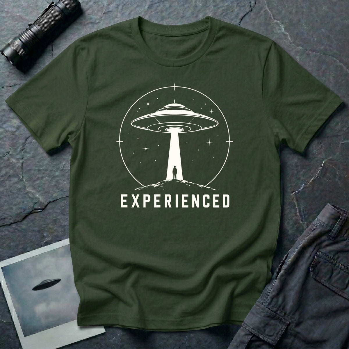 Experienced UFO T-shirt with a lone figure standing beneath the beam of a flying saucer inside a circular night-sky design. Military green tee