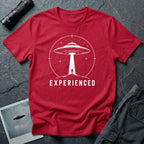 Experienced UFO T-shirt with a lone figure standing beneath the beam of a flying saucer inside a circular night-sky design. Red tee