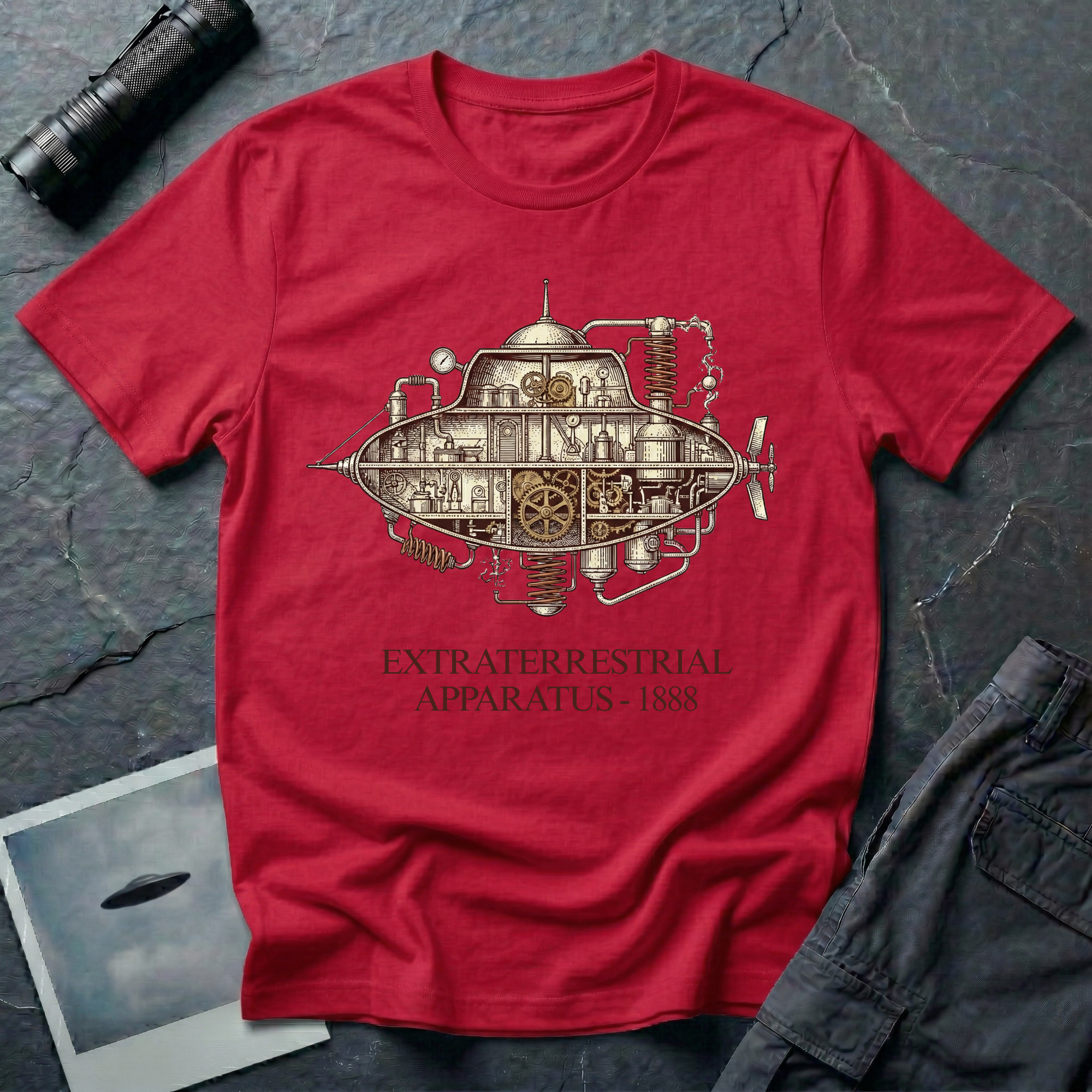 Extraterrestrial Apparatus steampunk UFO t-shirt — Victorian-era airship with exposed brass machinery gears and copper piping with "Extraterrestrial Apparatus 1888" caption on red cotton tee