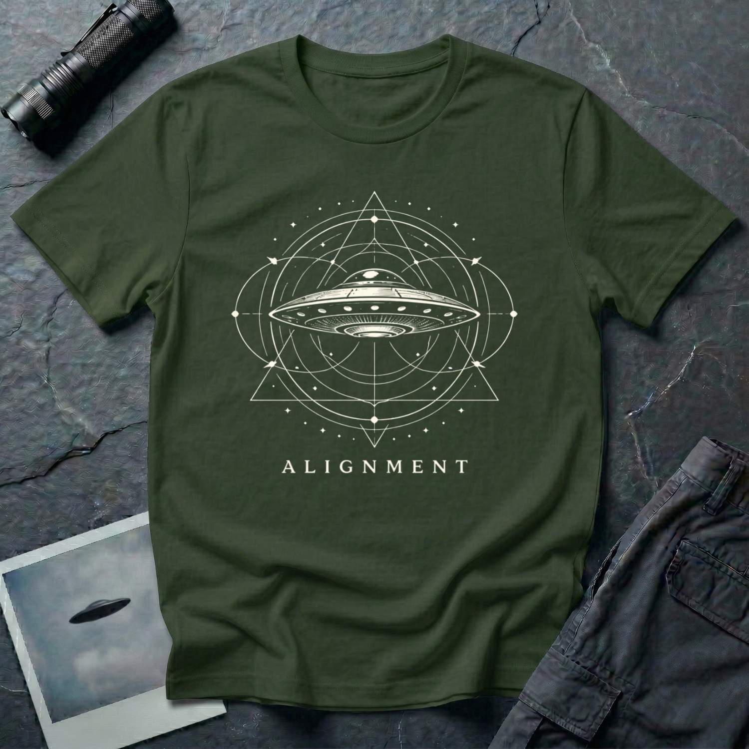 Alignment sacred geometry UFO t-shirt — flying saucer at the centre of a cosmological diagram with triangles and orbital rings in cream on military green cotton tee