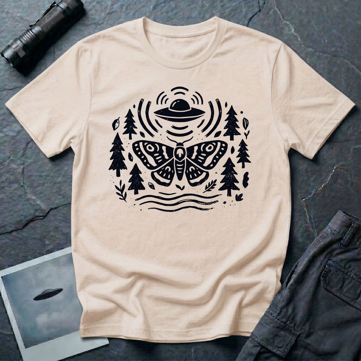Moth and UFO T-shirt with a folk-art moth beneath a flying saucer, surrounded by pine trees, leaves and radiating signal lines, on natural t-shirt