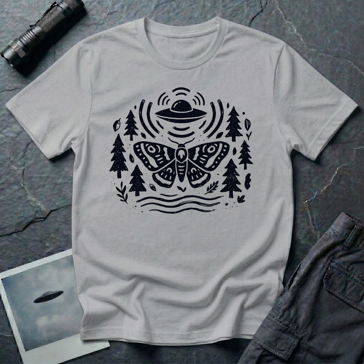 Moth and UFO T-shirt with a folk-art moth beneath a flying saucer, surrounded by pine trees, leaves and radiating signal lines, on sport grey t-shirt