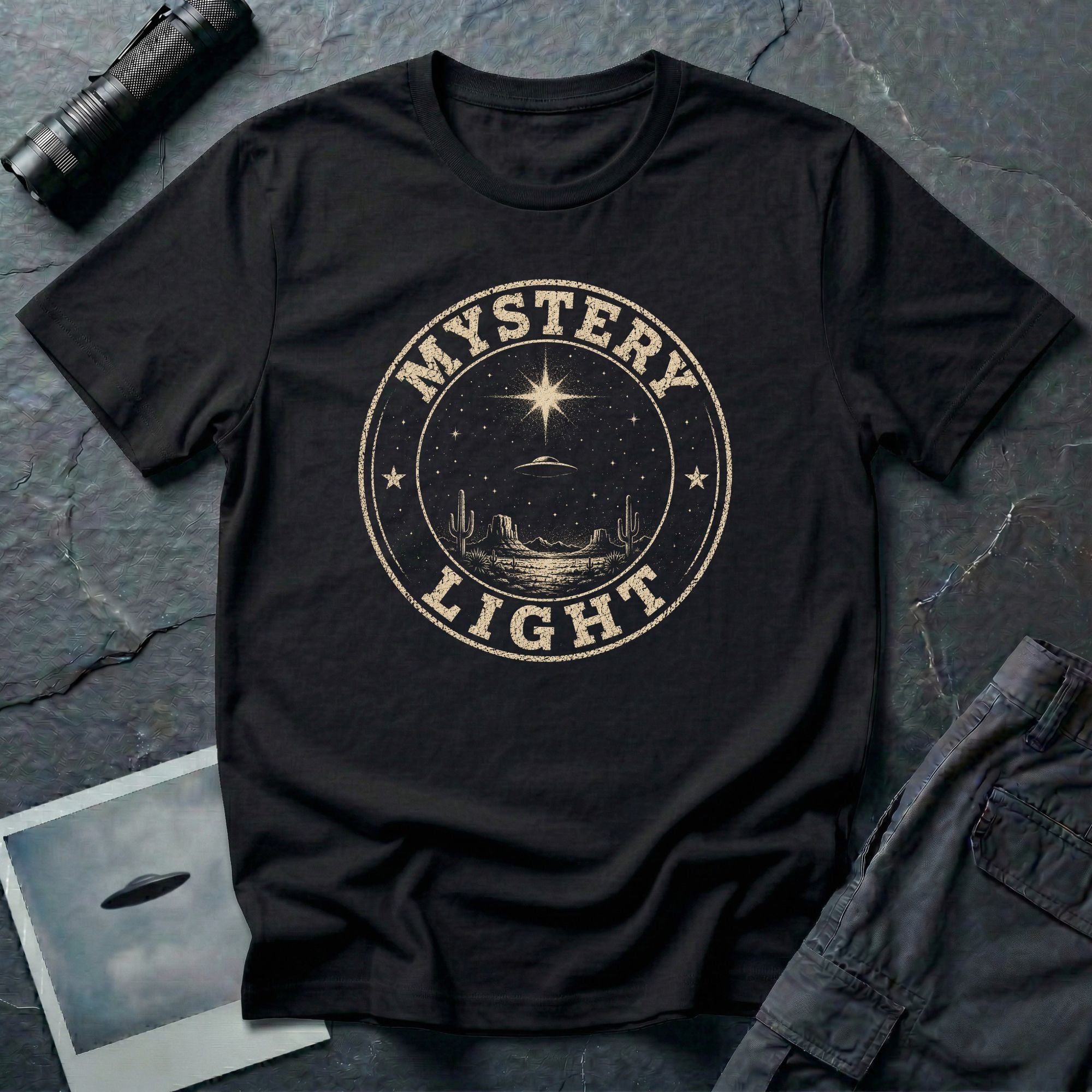 Black retro UFO t-shirt with a distressed circular badge showing a flying saucer over a desert landscape with cacti and the words MYSTERY LIGHT in gold