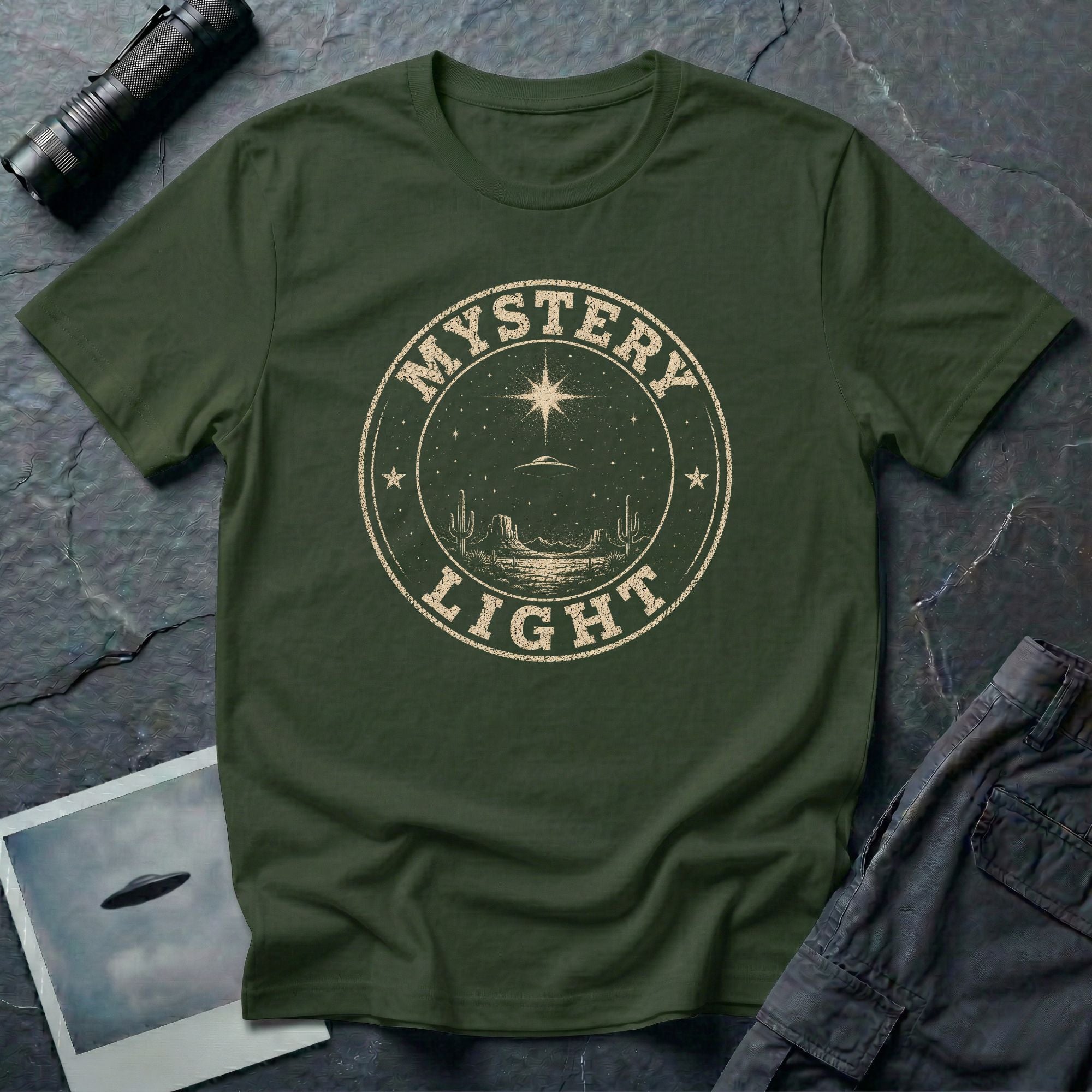 Green retro UFO t-shirt with a distressed circular badge showing a flying saucer over a desert landscape with cacti and the words MYSTERY LIGHT in gold