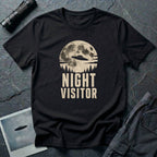Black retro UFO t-shirt with a flying saucer crossing a full moon over a conifer treeline with the words NIGHT VISITOR in distressed pale lettering