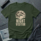 Military green retro UFO t-shirt with a flying saucer crossing a full moon over a conifer treeline with the words NIGHT VISITOR in distressed pale lettering