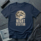 Navy blue retro UFO t-shirt with a flying saucer crossing a full moon over a conifer treeline with the words NIGHT VISITOR in distressed pale lettering
