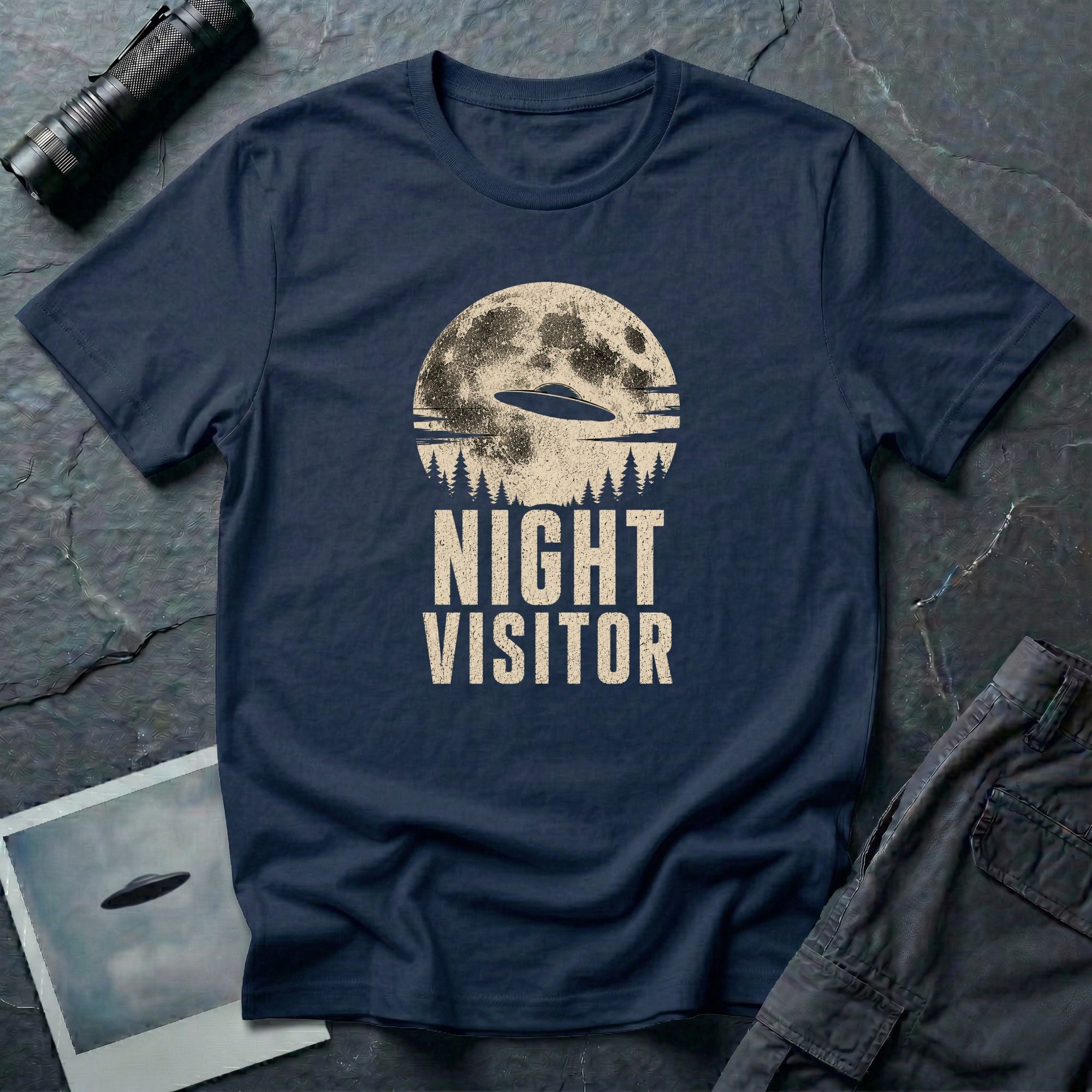 Navy blue retro UFO t-shirt with a flying saucer crossing a full moon over a conifer treeline with the words NIGHT VISITOR in distressed pale lettering
