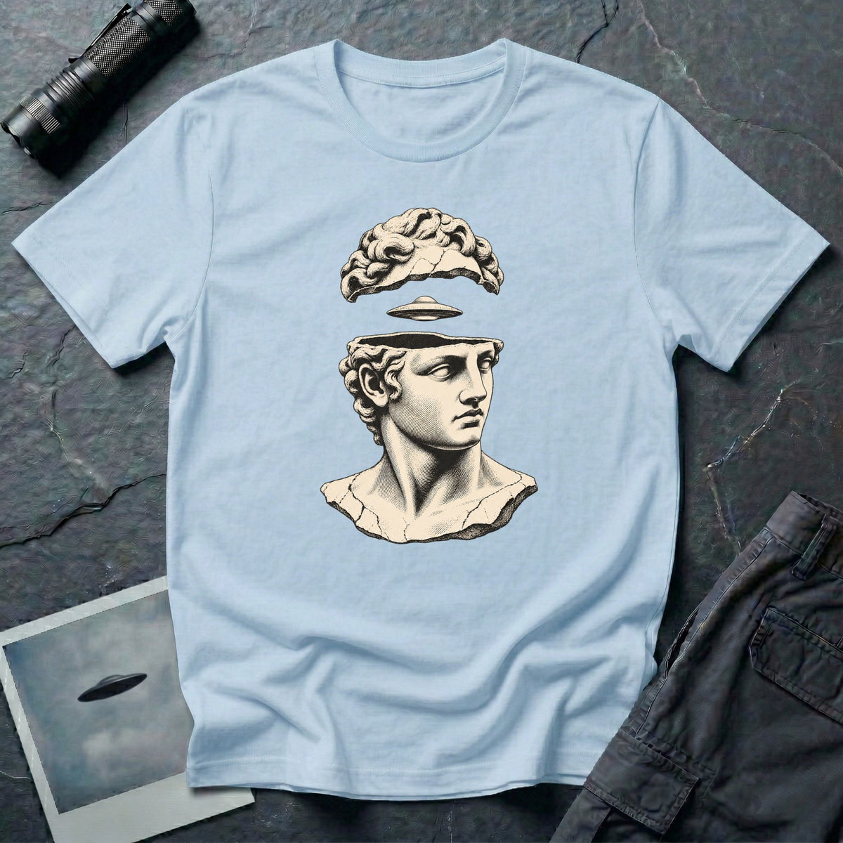 Classical marble bust with the top of the head lifted to reveal a UFO emerging, in cream engraving linework on a light blue t-shirt