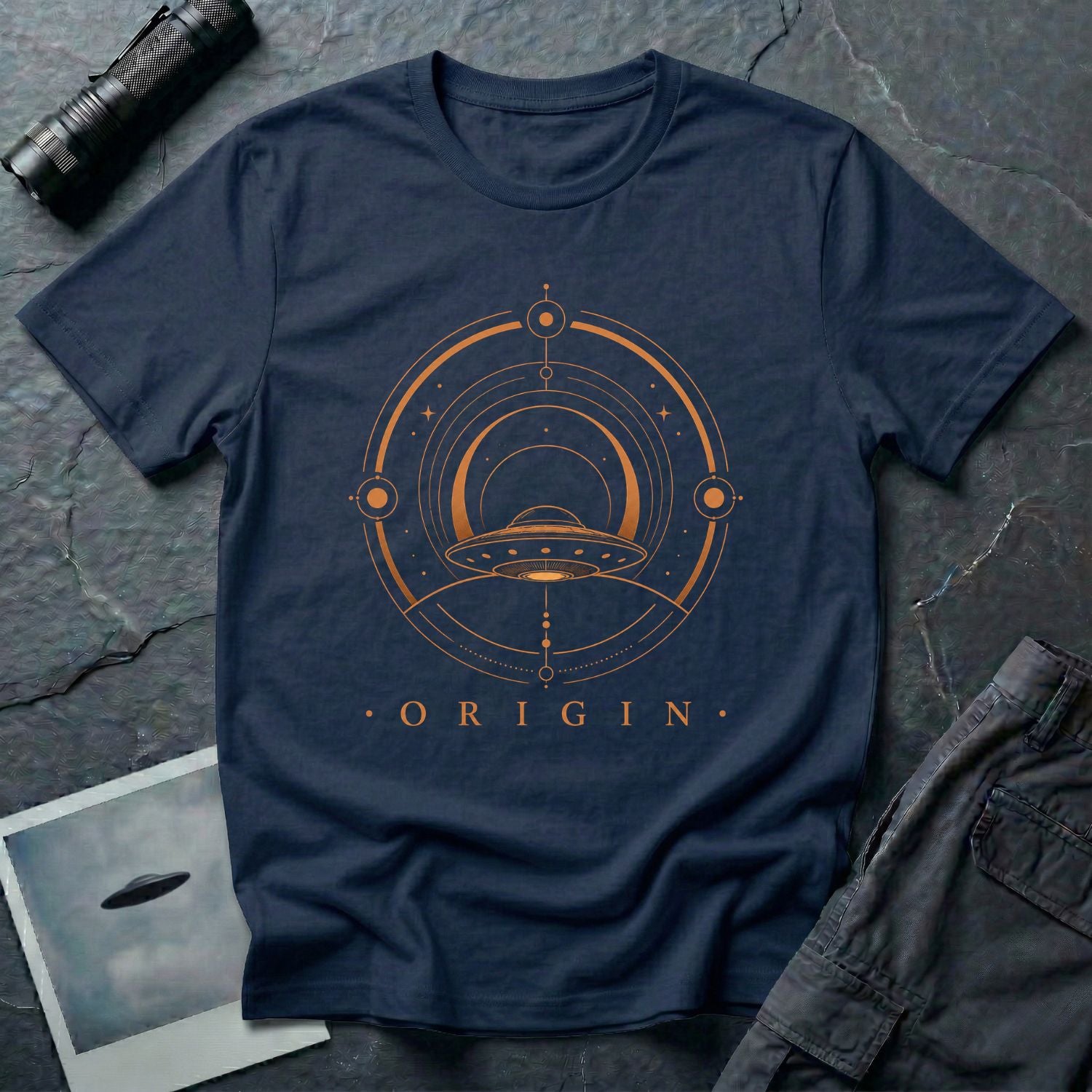Navy blue UFO t-shirt with a flying saucer emerging from concentric circular rings in copper with the word ORIGIN beneath