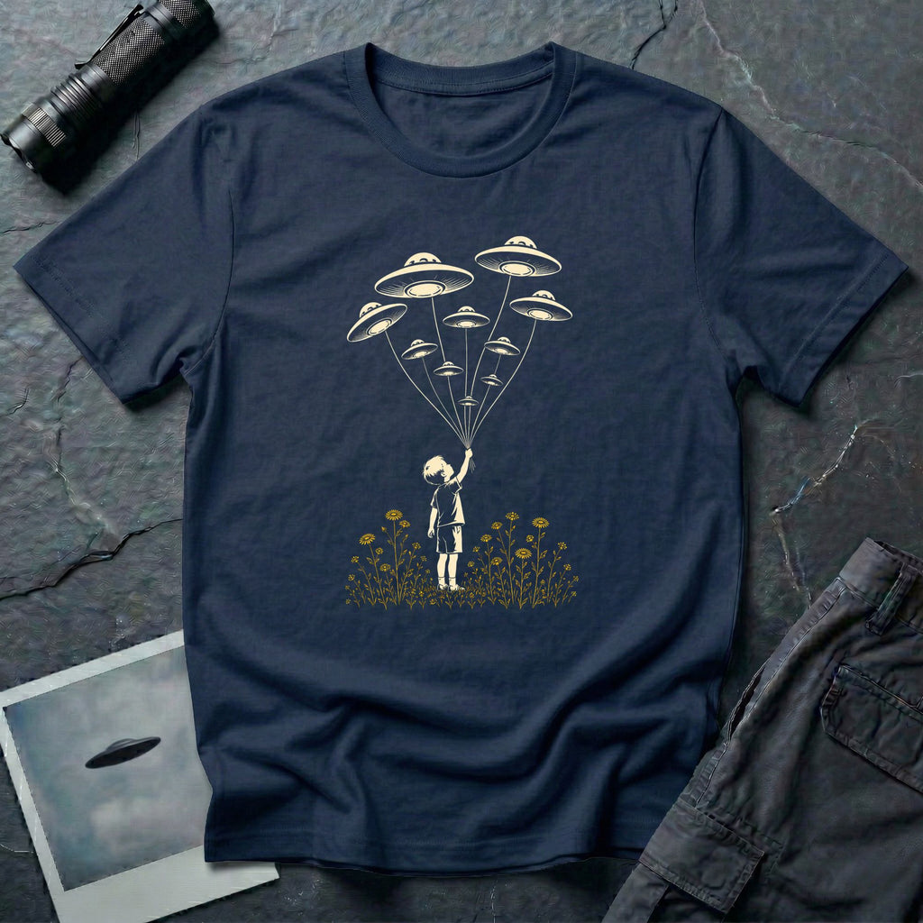 Stencil UFO t-shirt design, child reaching up to hold strings tethered to a small fleet of UFOs, orange wildflowers at the base, navy blue tee