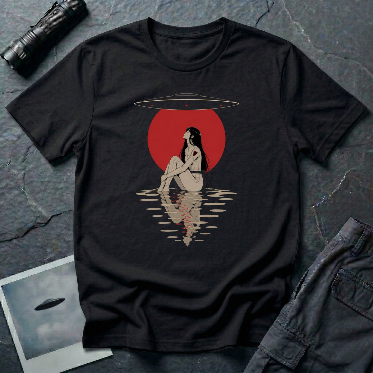 Black t-shirt with Japanese anime style illustrated figure sitting by water beneath a red sun and UFO, reflection visible in the water