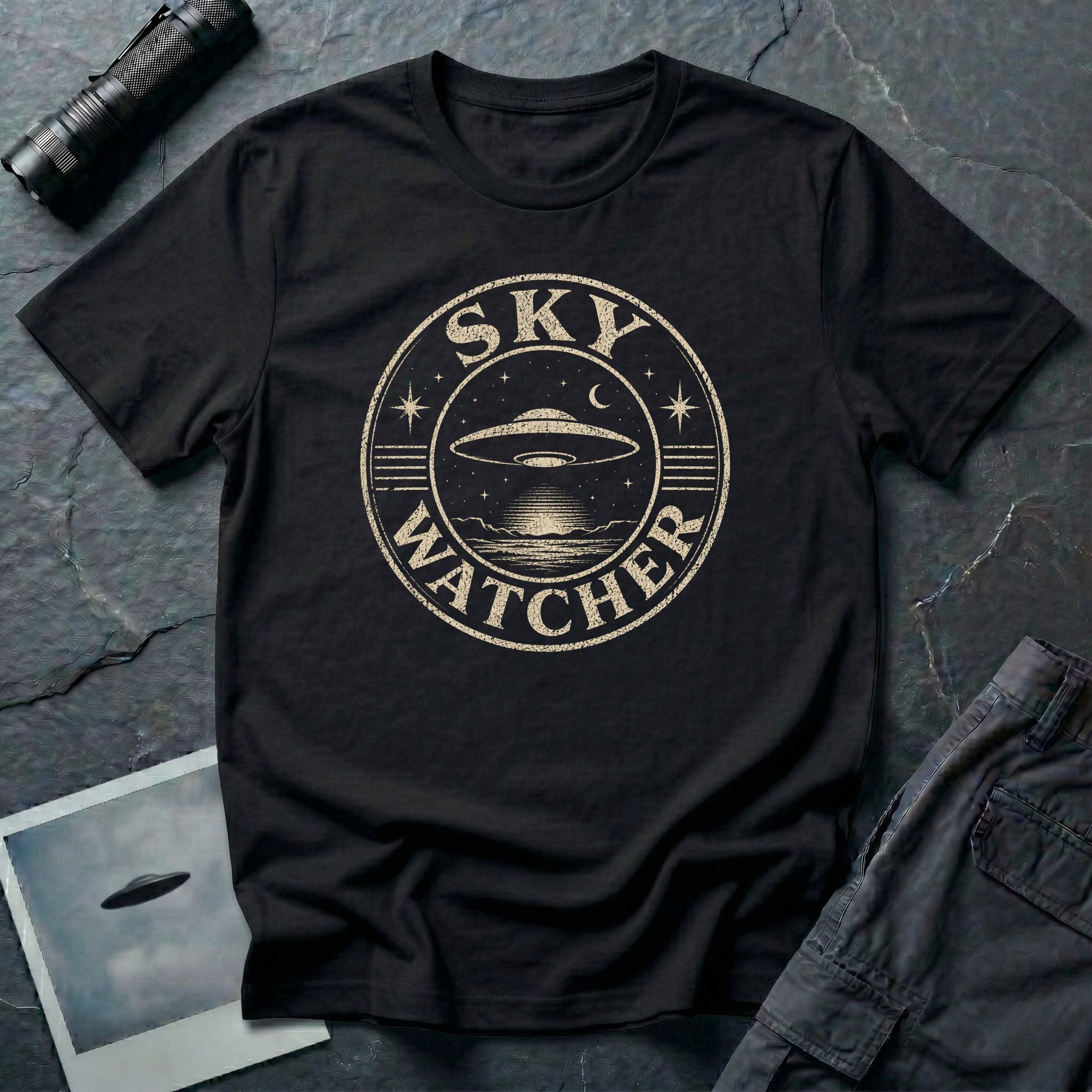Black retro UFO t-shirt with a distressed circular badge showing a flying saucer over water at night with a crescent moon and the words SKY WATCHER in pale lettering