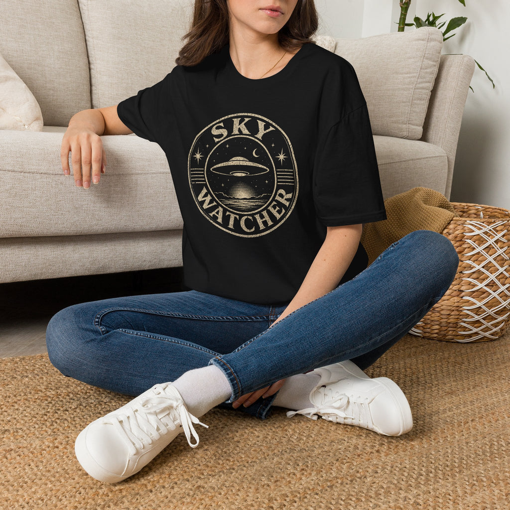 Model wearing black retro UFO t-shirt with a distressed circular badge showing a flying saucer over water at night with a crescent moon and the words SKY WATCHER in pale lettering