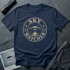 Navy blue retro UFO t-shirt with a distressed circular badge showing a flying saucer over water at night with a crescent moon and the words SKY WATCHER in pale lettering