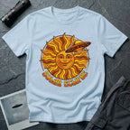 Solar Eclipse retro UFO t-shirt — smiling 1970s sun with flying saucer photobombing on pale blue unisex cotton tee