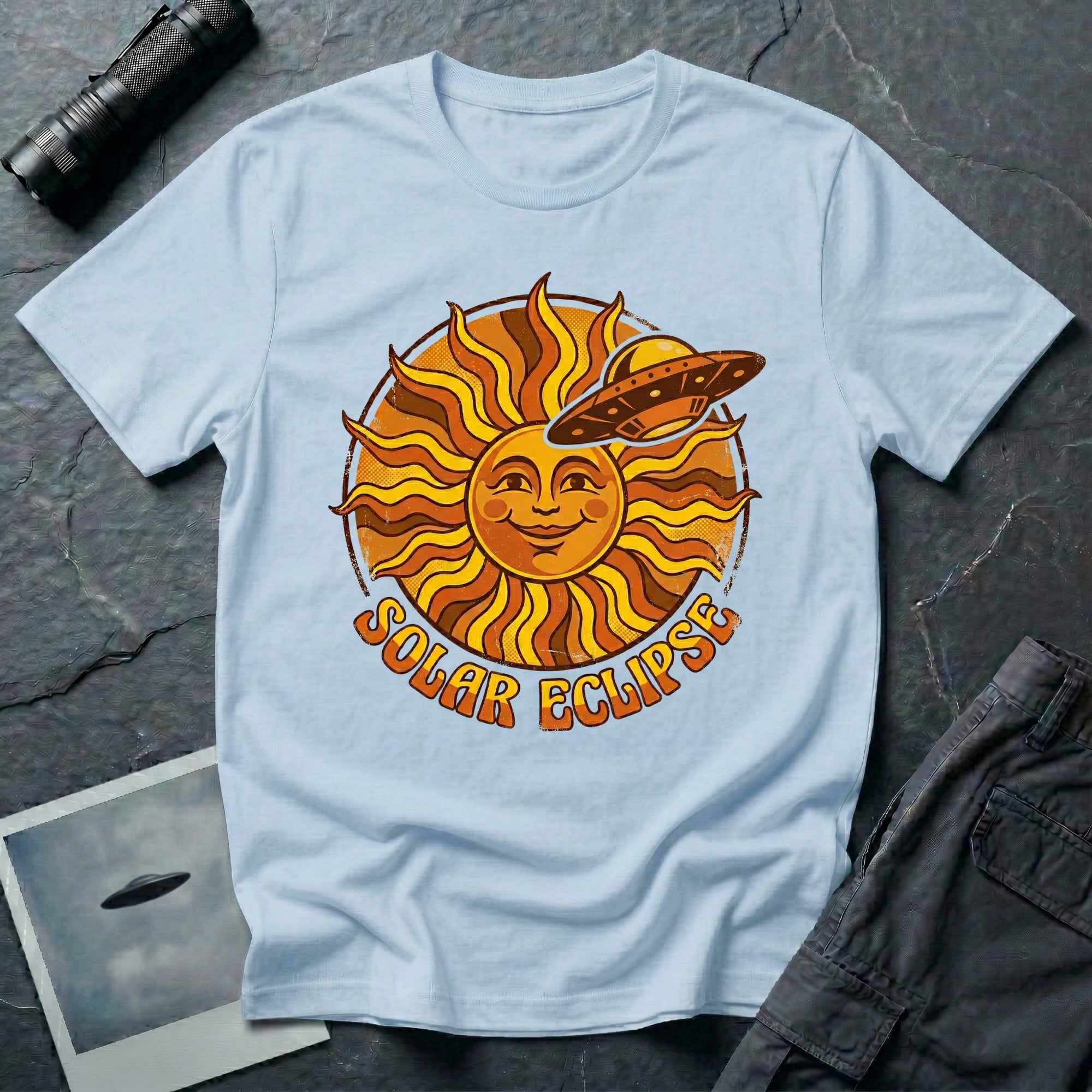 Solar Eclipse retro UFO t-shirt — smiling 1970s sun with flying saucer photobombing on pale blue unisex cotton tee