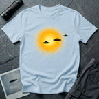 Solar Fly-by artistic UFO t-shirt — three black flying saucers passing across a glowing sun on light blue unisex cotton tee