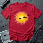 Solar Fly-by artistic UFO t-shirt — three black flying saucers passing across a glowing sun on red unisex cotton tee