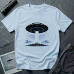 Light blue UFO t-shirt with massive mothership beaming light over city skyline at night