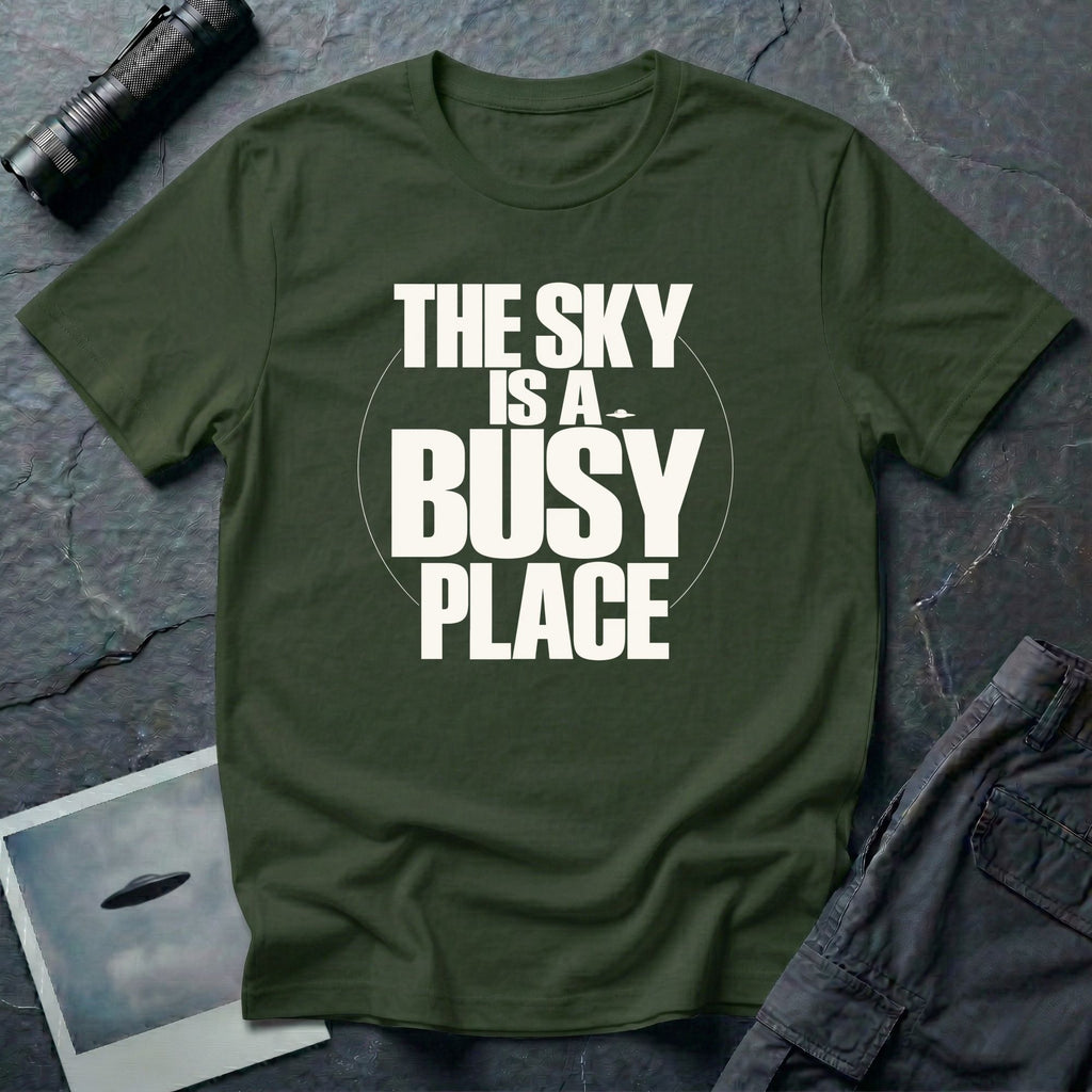 Military green t-shirt with bold white text reading The Sky Is A Busy Place and small UFO silhouette