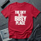 Red t-shirt with bold white text reading The Sky Is A Busy Place and small UFO silhouette