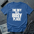 Royal blue t-shirt with bold white text reading The Sky Is A Busy Place and small UFO silhouette