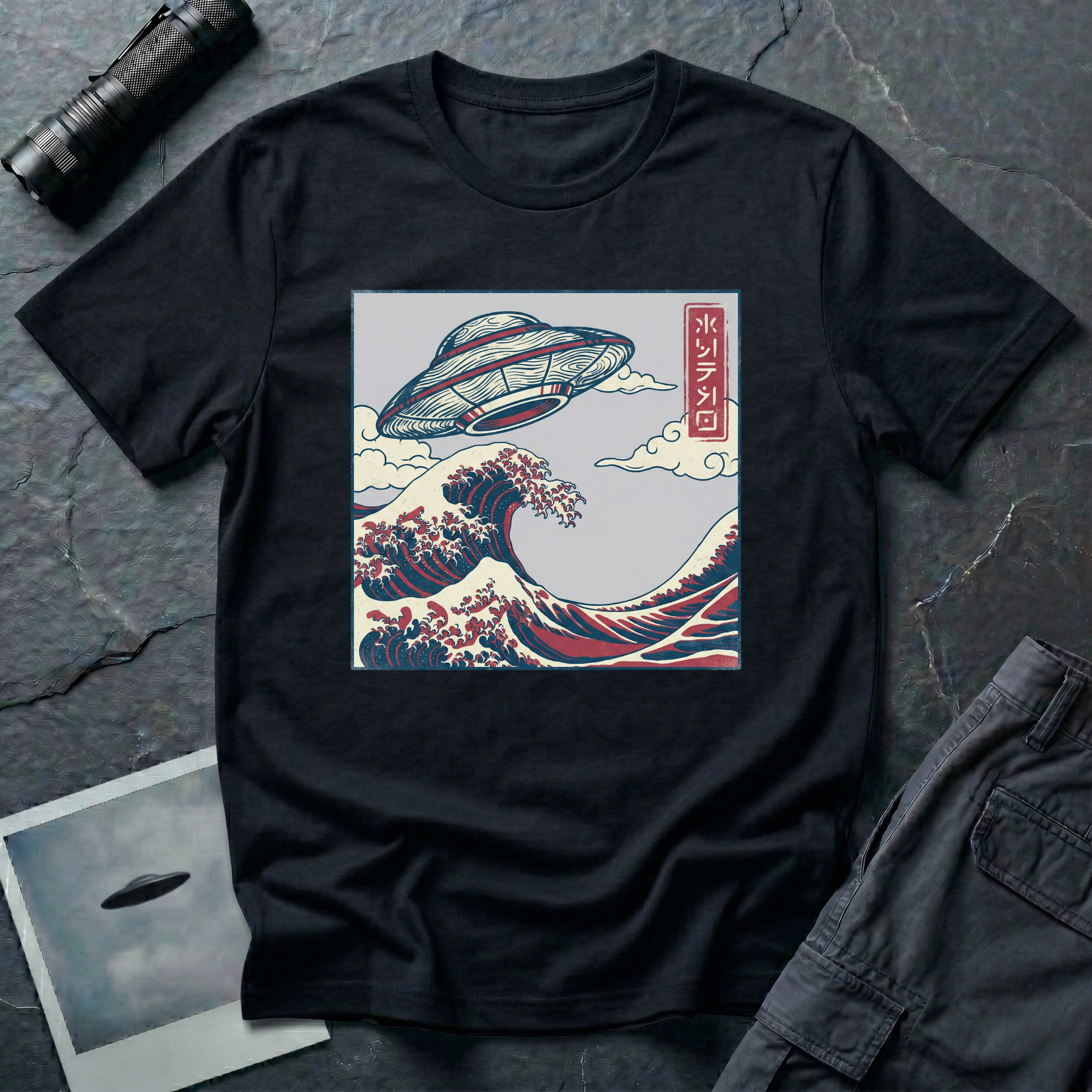 The Wave Japanese woodblock UFO t-shirt — flying saucer above Hokusai-style cresting wave in indigo and red on black cotton tee
