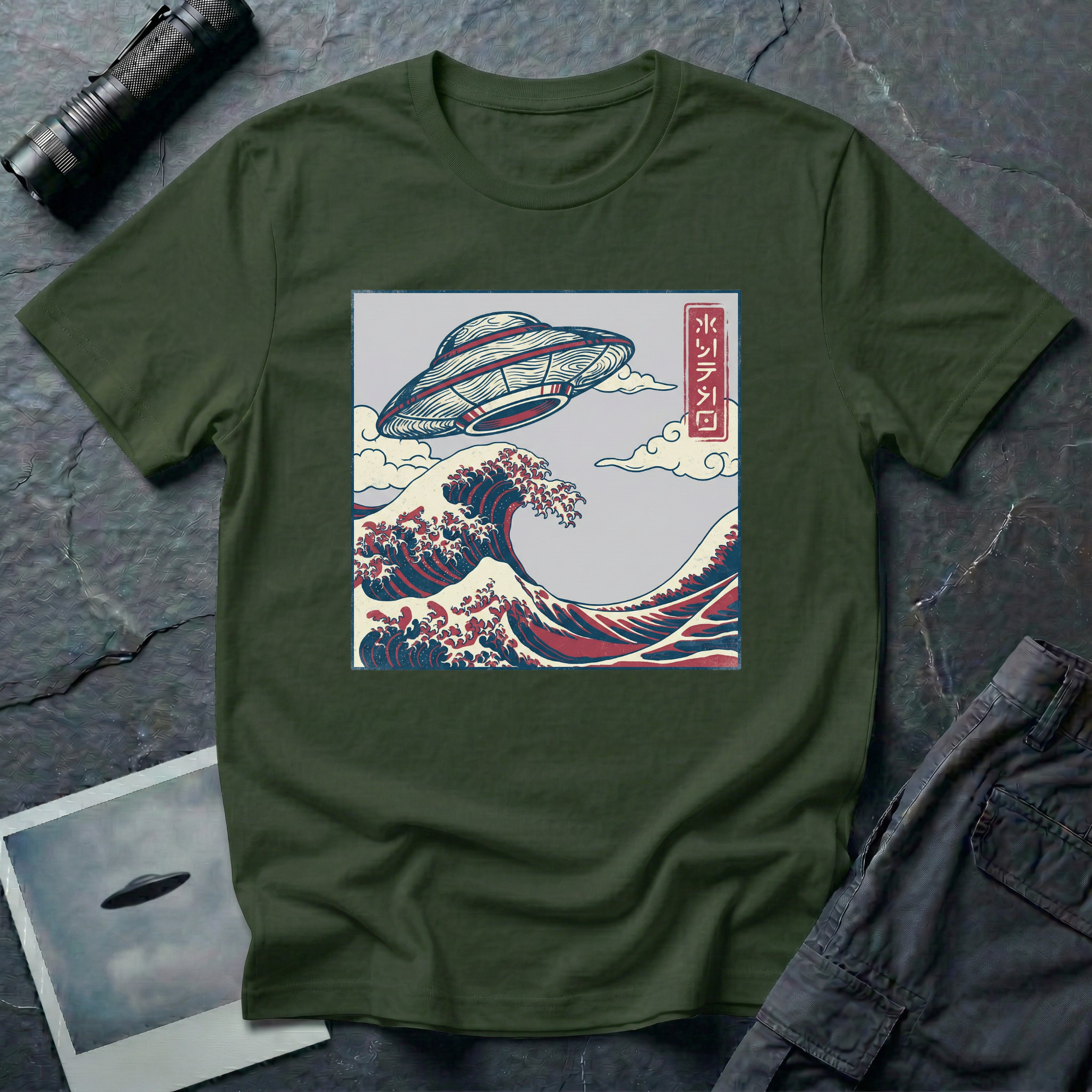The Wave Japanese woodblock UFO t-shirt — flying saucer above Hokusai-style cresting wave in indigo and red on green cotton tee