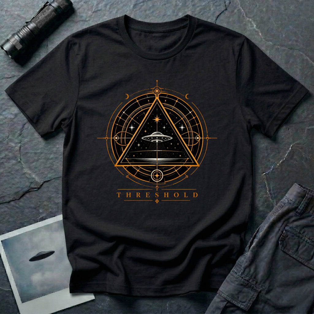 Black UFO t-shirt with a flying saucer inside an upward-pointing triangle portal with perspective grid, crescent moons, and compass frame in gold and black with the word THRESHOLD