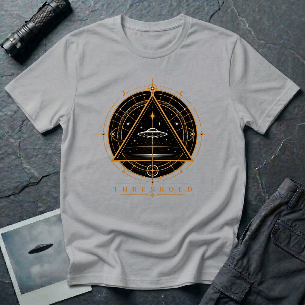 Grey UFO t-shirt with a flying saucer inside an upward-pointing triangle portal with perspective grid, crescent moons, and compass frame in gold and black with the word THRESHOLD