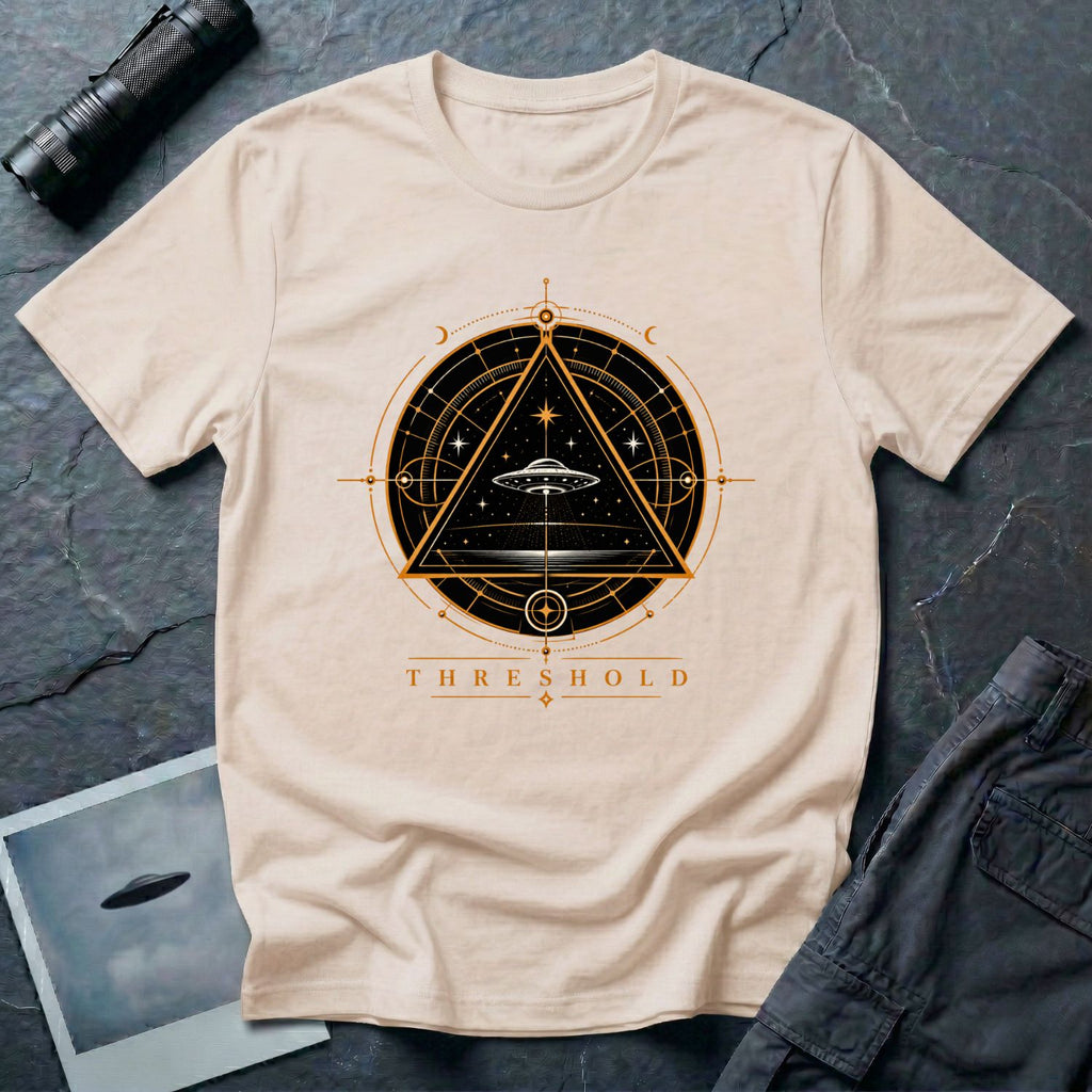 Natural UFO t-shirt with a flying saucer inside an upward-pointing triangle portal with perspective grid, crescent moons, and compass frame in gold and black with the word THRESHOLD