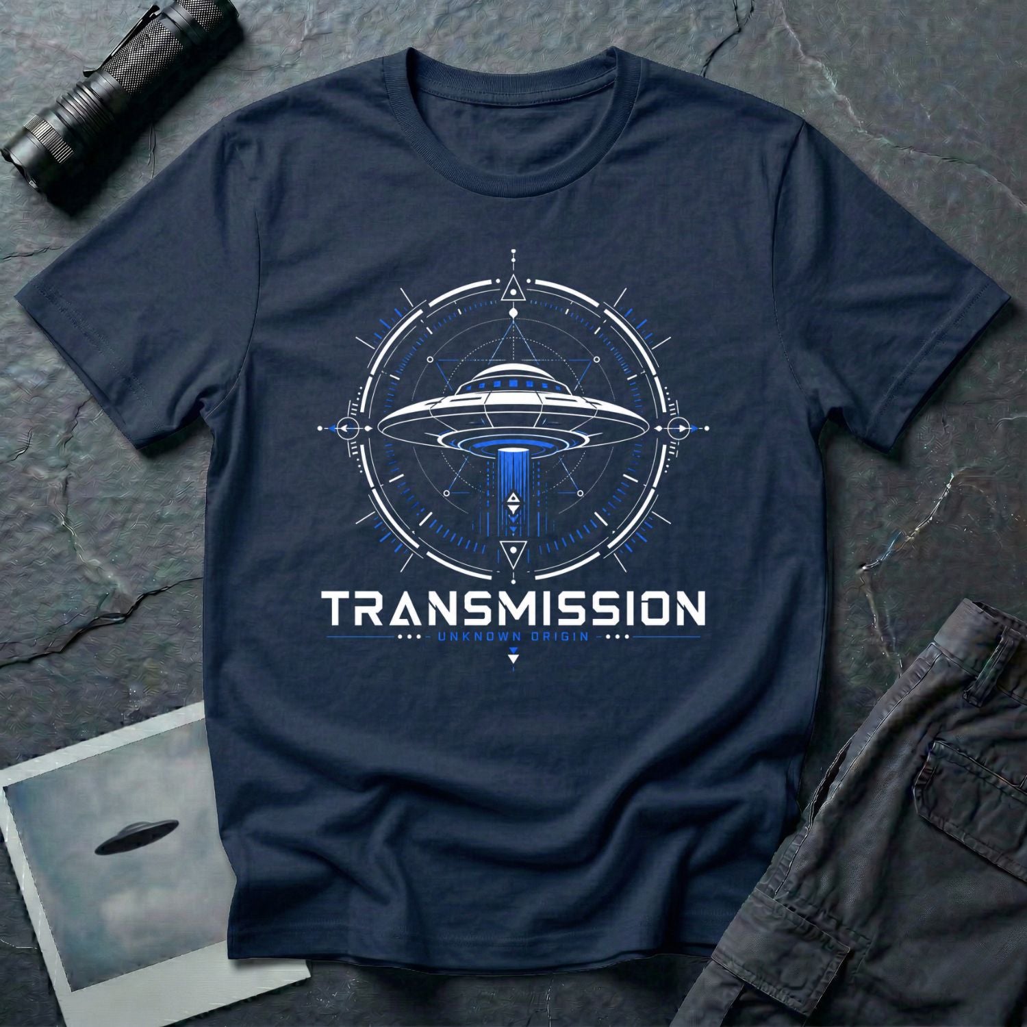 Navy blue UFO t-shirt with a flying saucer inside a sacred geometry compass and the words "TRANSMISSION · UNKNOWN ORIGIN ·" in white and blue