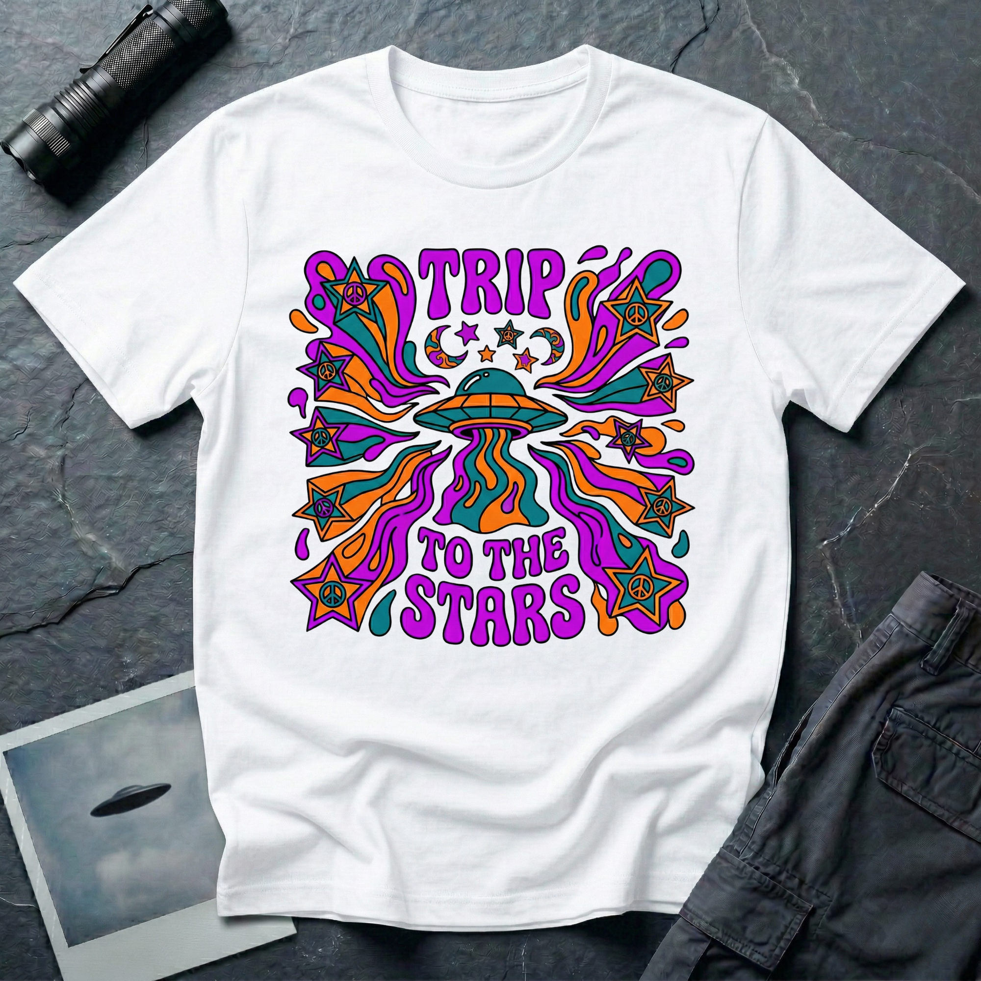 Trip To The Stars trippy UFO t-shirt — psychedelic saucer with paisley swirls and peace-sign stars in purple, teal, and orange on white cotton tee